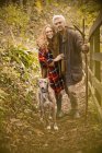 Porträt lächelndes Paar mit Hund und Spazierstock am Herbstzaun — Stockfoto