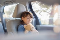 Girl with teddy bear sleeping in back seat of car — Stock Photo