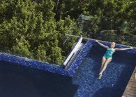 Femme flottant dans la piscine de luxe — Photo de stock