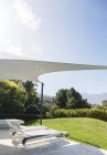 Terrasse de luxe moderne ensoleillée avec chaises longues sous auvent — Photo de stock