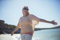 Donna anziana sorridente al sole sulla spiaggia — Foto stock