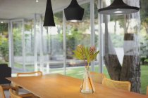 Modern black pendant lights hanging over bouquet on dining room table — Stock Photo