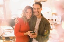 Retrato casal sorridente afetuoso usando telefone celular no bar — Fotografia de Stock