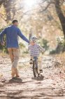 Father teaching son to ride bicycle on path in woods — Stock Photo