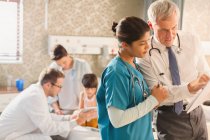 Ärztin und Krankenschwester machen Runde und sichten Krankenakte im Krankenhauszimmer — Stockfoto