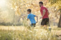 Отец и сын бегают в парке — стоковое фото