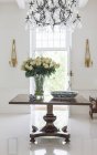 Lampadario sopra il bouquet sul tavolo nel foyer di lusso — Foto stock