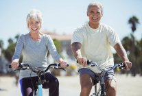 Porträt eines Senioren-Paares auf Fahrrädern am Strand — Stockfoto