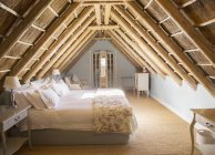 Sunny luxury attic bedroom under wooden roof — Stock Photo
