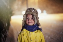 Portrait smiling boy in warm clothing standing in snowy road — Stock Photo