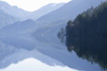 Montanhas refletidas em lago calmo durante o dia — Fotografia de Stock