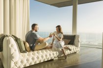 Casal brindar copos de vinho no luxuoso salão de chaise tufado com vista para o mar — Fotografia de Stock