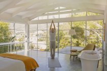 Älterer Mann praktiziert Yoga mit Händen über Kopf in Luxus-Schlafzimmer umklammert — Stockfoto