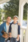 Porträt von Vater und Sohn mit Baseball und Handschuhen auf der Veranda — Stockfoto