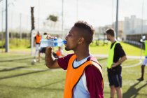 Soccer player drinking water on field — Stock Photo