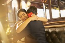 Woman with jewelry box hugging man in restaurant — Stock Photo