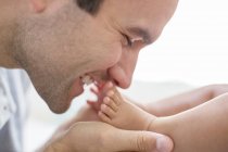 Father kissing baby boy's feet — Stock Photo