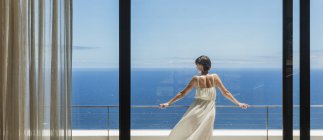 Mulher olhando para o oceano a partir da varanda — Fotografia de Stock