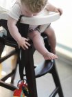 Bebê menina em cadeira alta atingindo para brinquedo — Fotografia de Stock