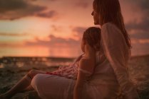Serene mother and daughter relaxing on beach at dusk — Stock Photo