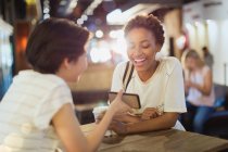 Молоді жінки друзі використовують мобільний телефон в кафе — стокове фото