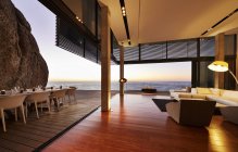 Moderno soggiorno di lusso aperto al patio con vista sul tramonto sull'oceano — Foto stock