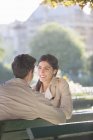 Young couple talking on park bench — Stock Photo