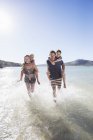 Família correndo na água na praia — Fotografia de Stock