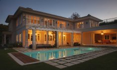 Casa de luxo iluminada com piscina à noite — Fotografia de Stock