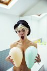 Exited woman covering breasts with balloons — Stock Photo