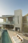 Couple standing on sunny modern luxury home showcase balcony over lap pool — Stock Photo