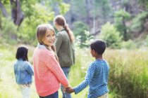 Дети держатся за руки в поле — стоковое фото