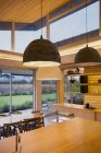 Pingentes modernos iluminados pendurados sobre ilha de cozinha de madeira — Fotografia de Stock