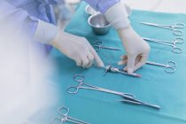 Cirurgião em luvas de borracha preparando instrumentos cirúrgicos na bandeja — Fotografia de Stock
