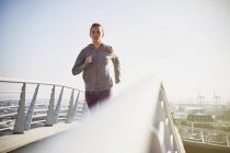 Läuferin läuft auf sonnigem städtischen Steg — Stockfoto