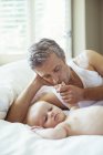 Père embrassant la main du bébé sur le lit — Photo de stock