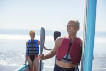 Felice coppia di anziani con paddleboard sulla spiaggia — Foto stock