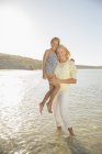 Grandmother holding granddaughter in waves — Stock Photo
