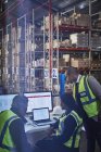 Gestionnaires d'ordinateurs portables et d'ordinateurs dans un entrepôt de distribution — Photo de stock