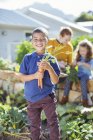 Мальчик держит кучу моркови в саду — стоковое фото