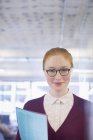 Happy young businesswoman holding folder in office — Stock Photo