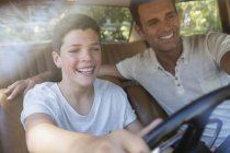 Feliz padre enseñando hijo a conducir coche - foto de stock