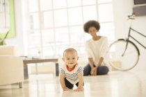 Mutter sieht Baby auf Wohnzimmerboden krabbeln — Stockfoto