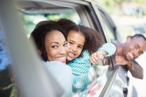 Portrait of happy family leaning out car windows — Stock Photo
