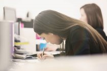 Фокусована бізнес-леді, що пише за столом в офісі — стокове фото