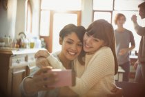 Young women friends taking selfie with camera phone in apartment — Stock Photo