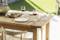 Vino y aperitivo en mesa de comedor de madera en el patio - foto de stock