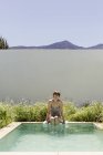 Donna immergendo le gambe in piscina lap di lusso — Foto stock
