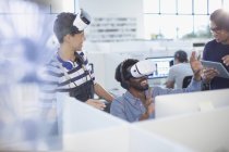 Programadores informáticos probando simuladores de realidad virtual en la oficina - foto de stock