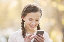 Крупним планом усміхнена дівчина смс з мобільним телефоном на відкритому повітрі — стокове фото
